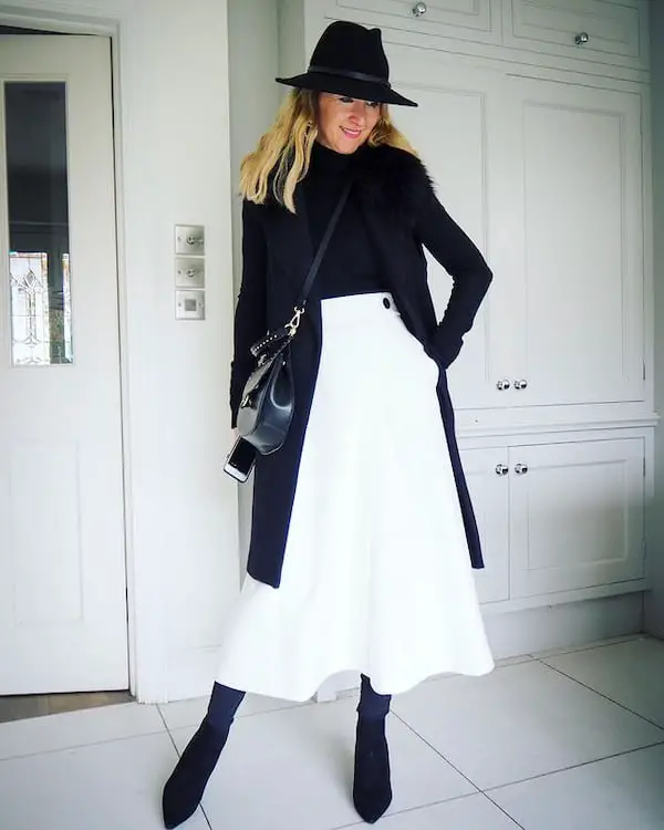 White Midi Skirt with Black Top + Black Trench Coat + Black Boots + Black Hat + Cross Shoulder Handbag