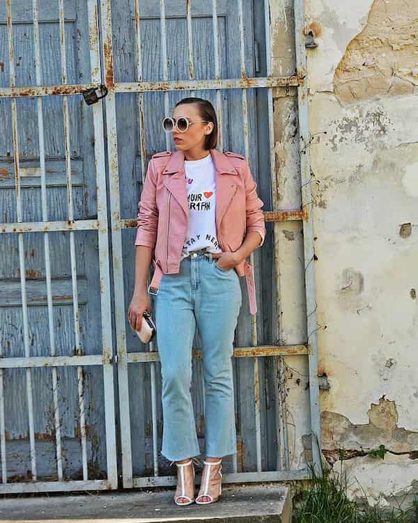 White Heels and Blue High Waist Flared legs Jeans with White Graphic Shirt + Pink Biker Jacket + Sunglasses